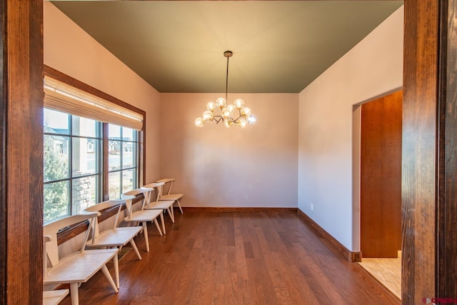 unfurnished dining area featuring a chandelier and wood-type flooring