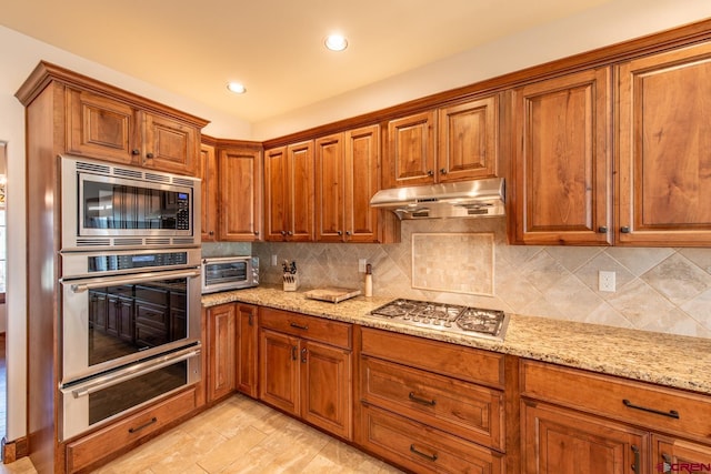 kitchen featuring backsplash, light stone countertops, and appliances with stainless steel finishes