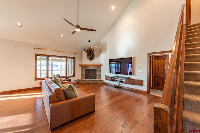 living room with hardwood / wood-style flooring, ceiling fan, a fireplace, and high vaulted ceiling