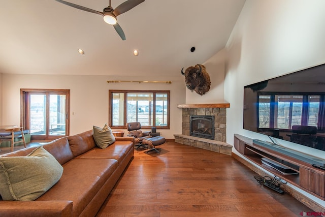 living room with ceiling fan, a healthy amount of sunlight, a stone fireplace, and wood-type flooring