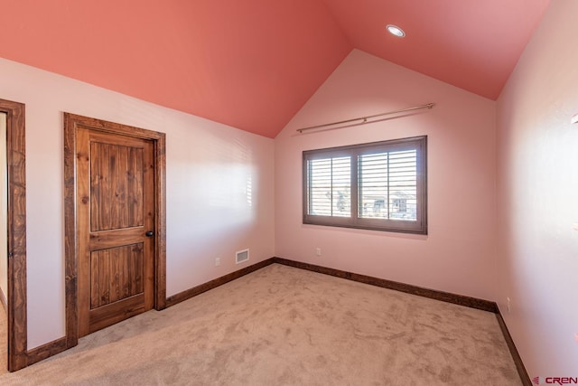 carpeted spare room featuring vaulted ceiling