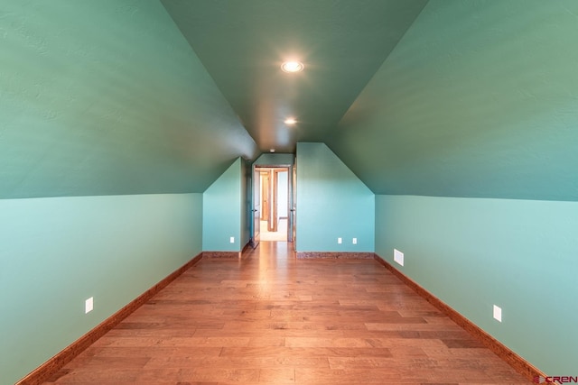 bonus room with vaulted ceiling and light hardwood / wood-style flooring