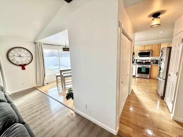 corridor featuring light hardwood / wood-style flooring and lofted ceiling