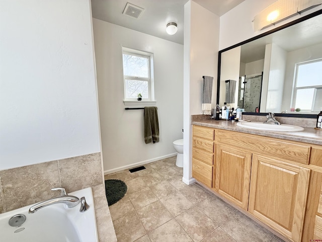 bathroom featuring tile patterned flooring, vanity, toilet, and a tub to relax in