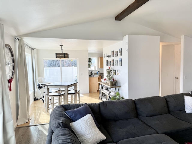 living room featuring lofted ceiling with beams and light hardwood / wood-style flooring