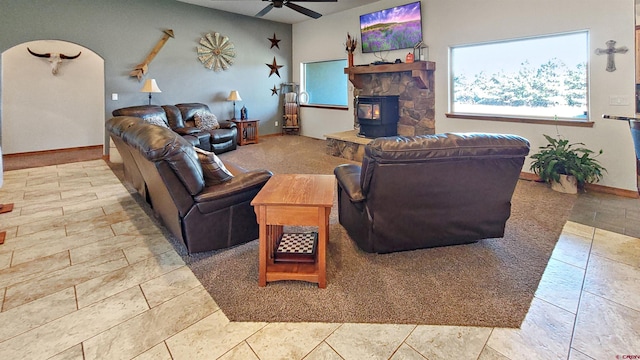 living room with a wood stove, ceiling fan, and light tile patterned flooring