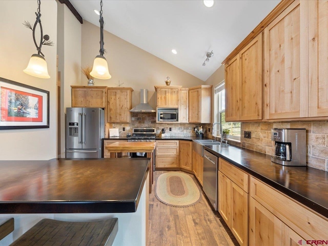 kitchen featuring sink, wall chimney exhaust hood, tasteful backsplash, decorative light fixtures, and appliances with stainless steel finishes