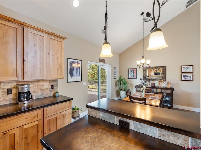 kitchen featuring lofted ceiling, hanging light fixtures, decorative backsplash, light brown cabinetry, and a notable chandelier