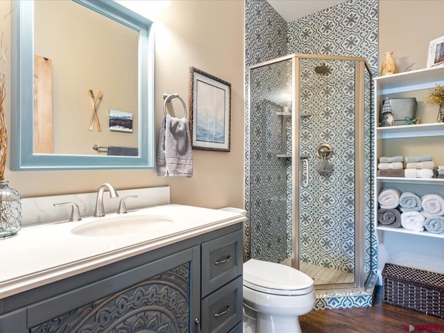 bathroom featuring hardwood / wood-style floors, vanity, toilet, and a shower with shower door