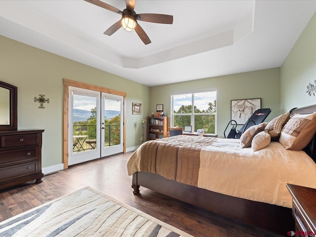 bedroom featuring a tray ceiling, ceiling fan, wood-type flooring, and access to outside