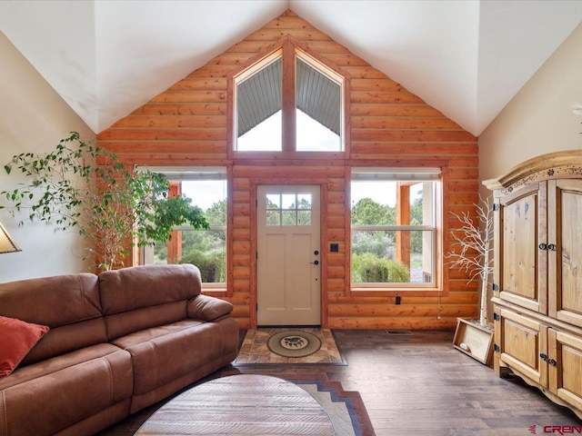 living room with high vaulted ceiling, rustic walls, and dark wood-type flooring