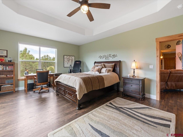 bedroom with a raised ceiling, ceiling fan, and dark wood-type flooring