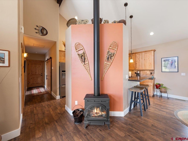 interior space with a wood stove, high vaulted ceiling, and dark wood-type flooring