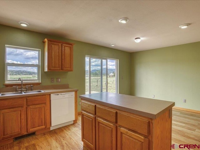 kitchen with dishwasher, a center island, light hardwood / wood-style flooring, and sink