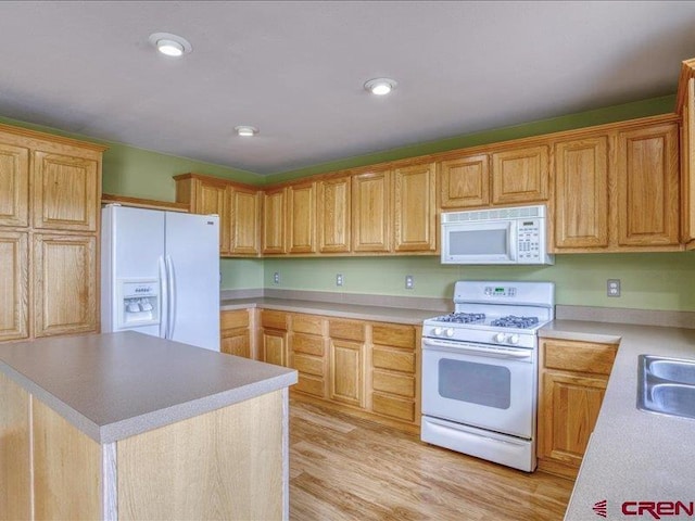 kitchen with sink, a kitchen island, light hardwood / wood-style floors, and white appliances