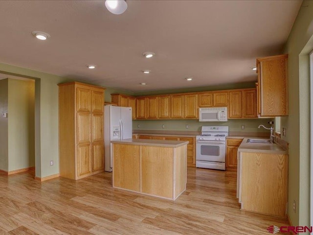 kitchen featuring a center island, white appliances, sink, and light hardwood / wood-style flooring