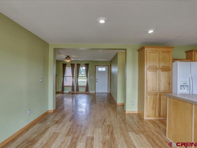 interior space with ceiling fan, light brown cabinets, white refrigerator with ice dispenser, and light hardwood / wood-style flooring