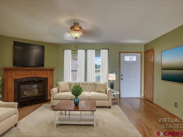 living room with a tile fireplace, light hardwood / wood-style flooring, and ceiling fan