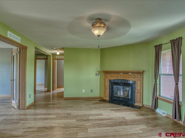 unfurnished living room featuring a fireplace, a wealth of natural light, light wood-type flooring, and ceiling fan