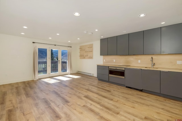 kitchen featuring sink, baseboard heating, light hardwood / wood-style floors, gray cabinets, and appliances with stainless steel finishes