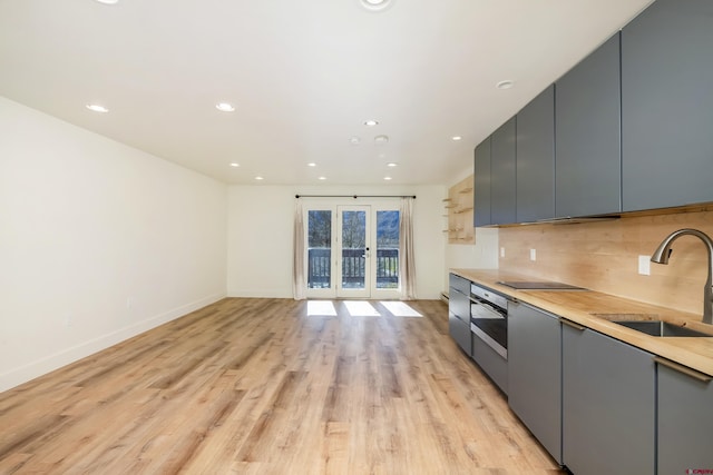 kitchen with decorative backsplash, light wood-type flooring, gray cabinetry, black electric cooktop, and sink