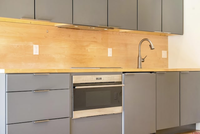 kitchen featuring gray cabinetry, stainless steel oven, exhaust hood, and white refrigerator