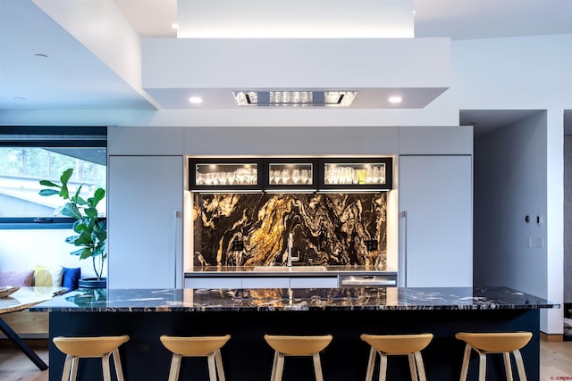 kitchen with a kitchen bar and dark stone countertops