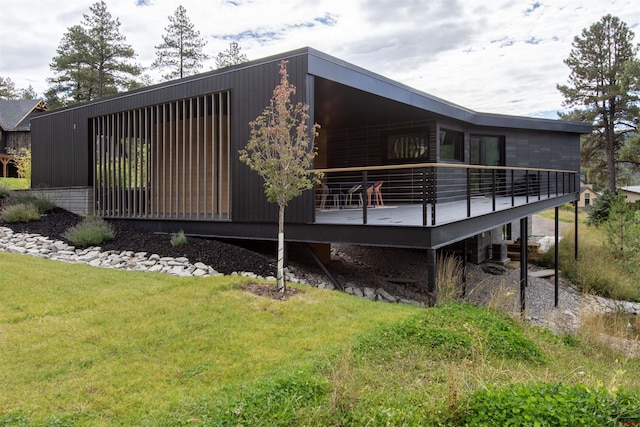 rear view of house featuring a lawn and central AC