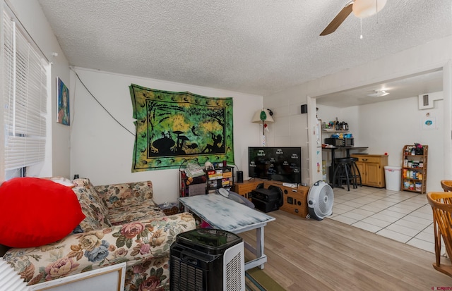 living room with light tile patterned floors, a textured ceiling, and ceiling fan