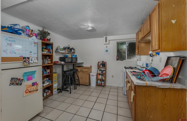 kitchen with white gas range, light tile patterned flooring, and a textured ceiling