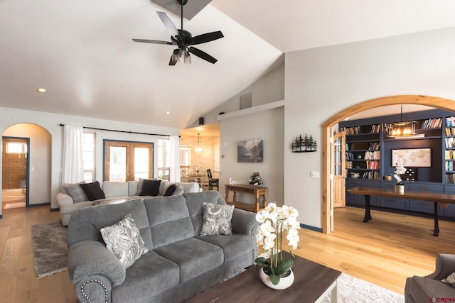 living room featuring french doors, ceiling fan with notable chandelier, hardwood / wood-style flooring, and high vaulted ceiling