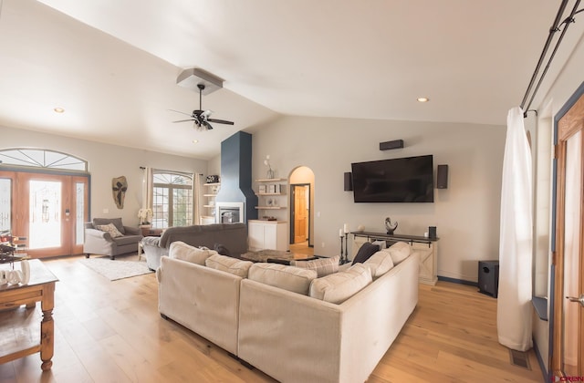 living room with ceiling fan, light wood-type flooring, and vaulted ceiling