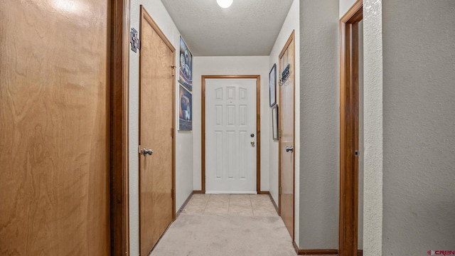 hallway featuring light colored carpet and a textured ceiling