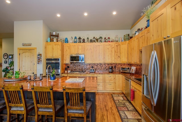 kitchen with decorative backsplash, appliances with stainless steel finishes, sink, light brown cabinets, and light hardwood / wood-style floors