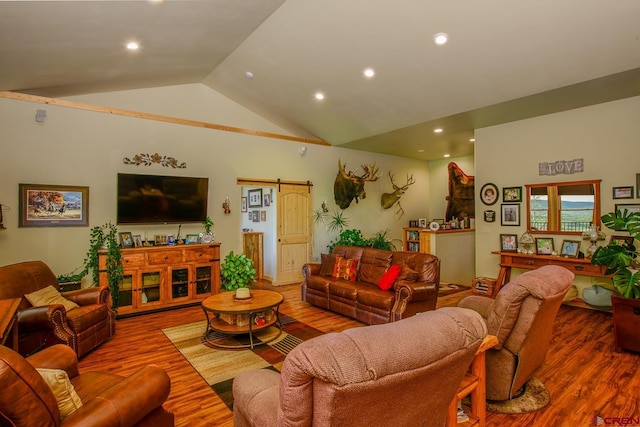 living room featuring a barn door, hardwood / wood-style flooring, and lofted ceiling