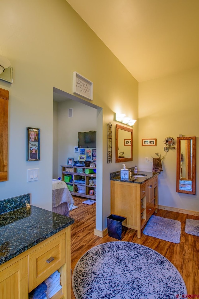 bathroom with hardwood / wood-style flooring, vanity, and lofted ceiling