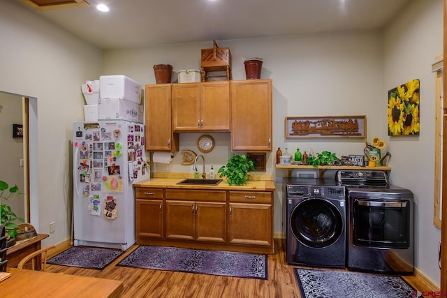 kitchen featuring washer and clothes dryer, sink, light hardwood / wood-style flooring, and white refrigerator