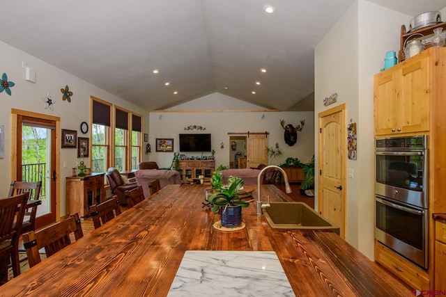 dining space with wood-type flooring, lofted ceiling, and sink