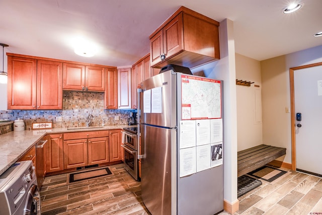 kitchen featuring backsplash, sink, light stone countertops, washer / dryer, and stainless steel appliances