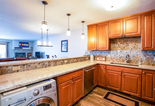 kitchen featuring pendant lighting, a stone fireplace, sink, tasteful backsplash, and washer / dryer