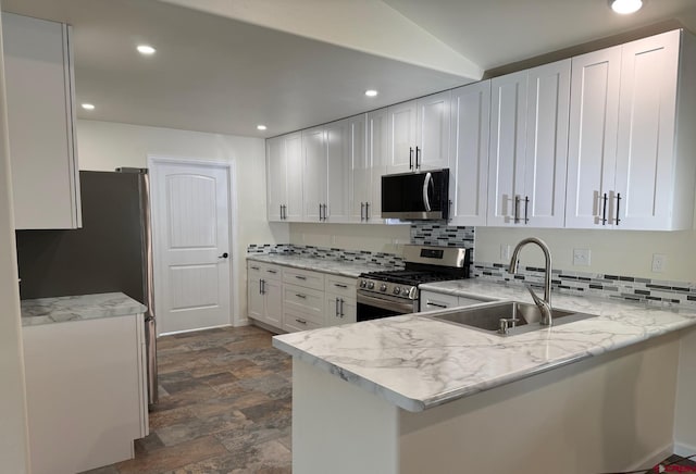 kitchen with kitchen peninsula, sink, white cabinetry, light stone counters, and stainless steel appliances