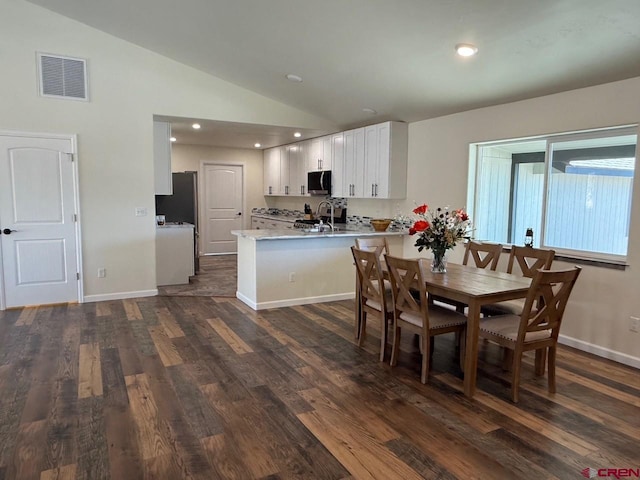 dining area with sink, dark wood-type flooring, and lofted ceiling