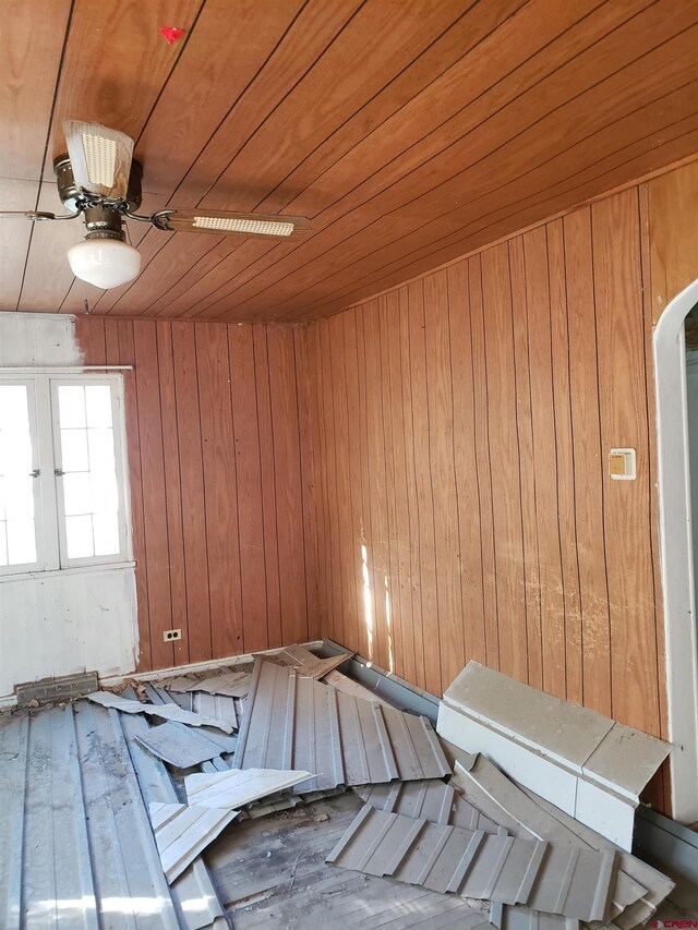 interior space with wood walls, ceiling fan, and wooden ceiling