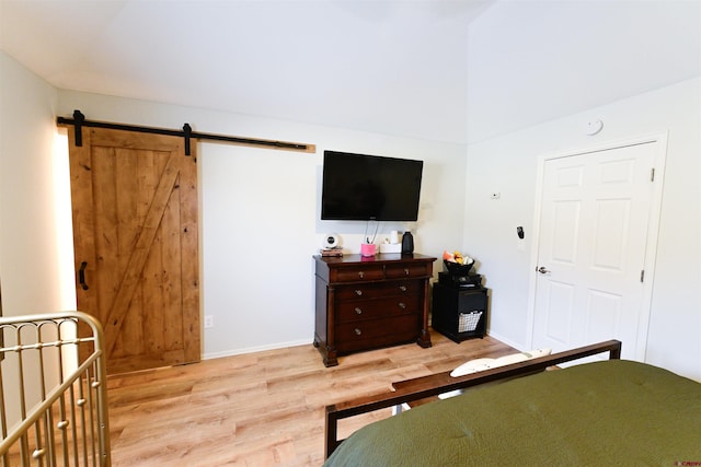 bedroom featuring a barn door and light hardwood / wood-style flooring