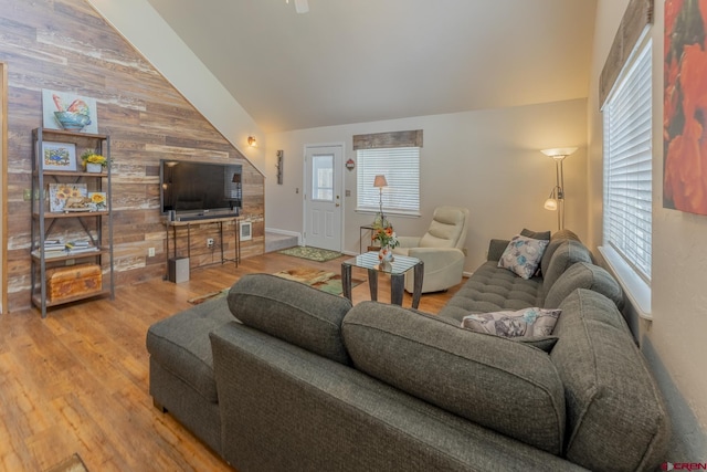 living room featuring wood walls, hardwood / wood-style floors, and vaulted ceiling