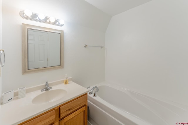 bathroom with vanity, a tub to relax in, and vaulted ceiling