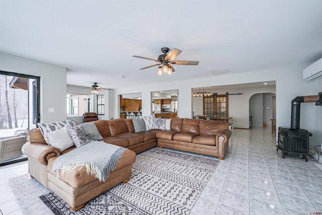 living room featuring a wall mounted air conditioner, a wood stove, and ceiling fan