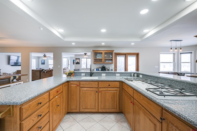 kitchen featuring a raised ceiling, light tile patterned floors, sink, and stainless steel gas cooktop