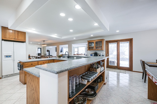 kitchen with plenty of natural light, white refrigerator with ice dispenser, a kitchen island with sink, and a tray ceiling