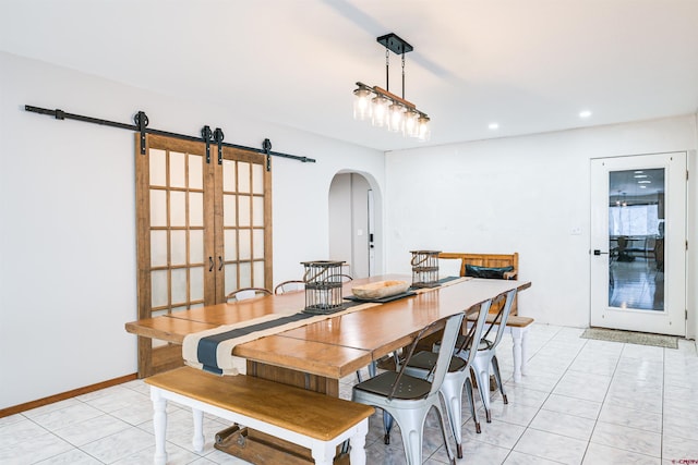 dining area with light tile patterned floors, a barn door, and french doors